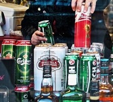 person selecting alcohol from stack of cans